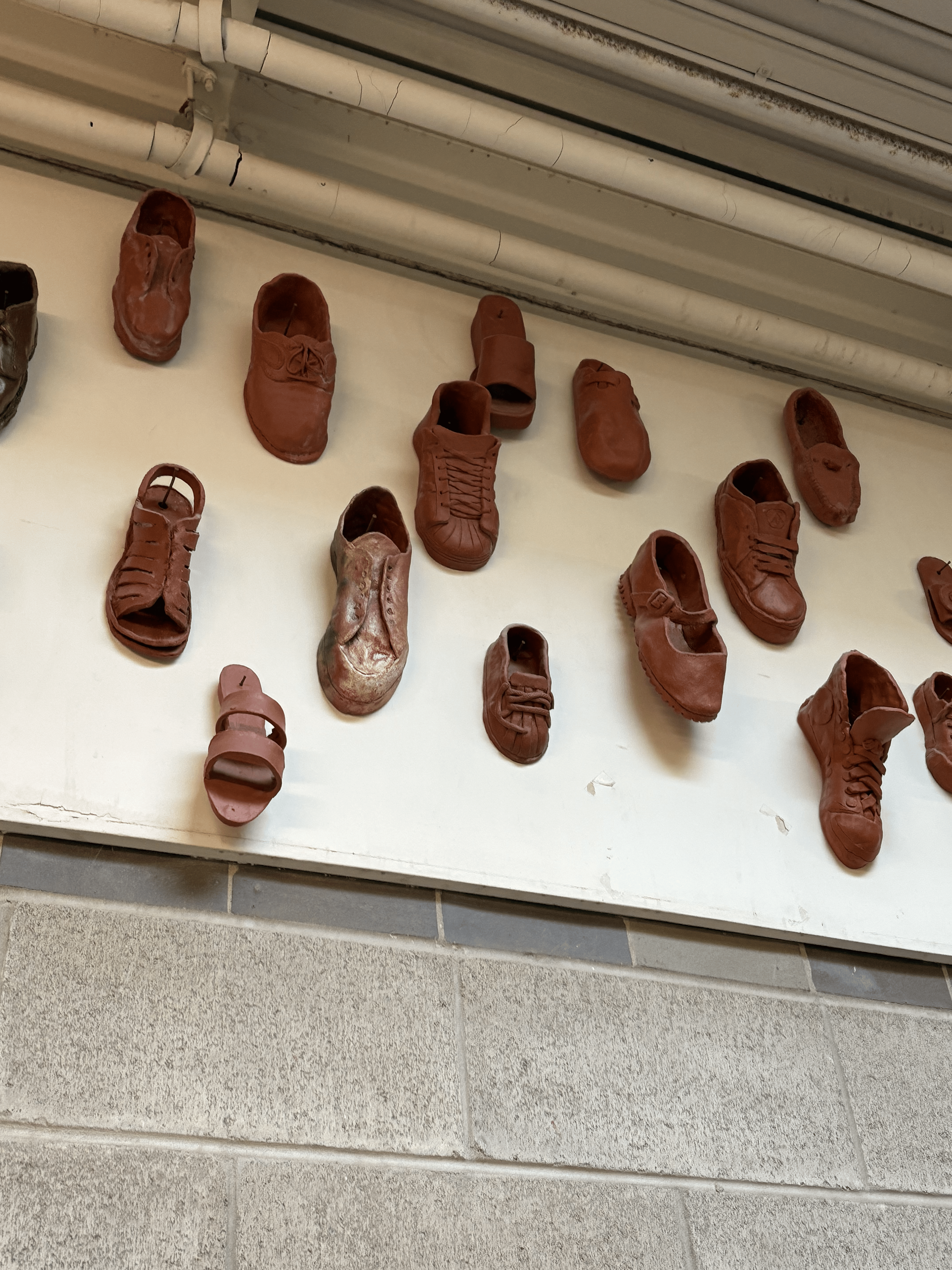 ceramic made 3d shoes, objects are made from clay which is then dried and nailed onto the wall/a board, made in the craft and design (ceramics) program at sheridan